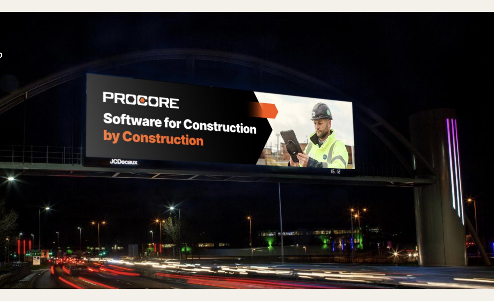 Procore campaign on a large JCDecaux digital billboard spanning a motorway bridge at night, reading 'Software for Construction, by Construction'.